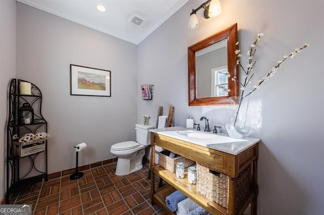 half bathroom with brick floor, recessed lighting, visible vents, toilet, and a sink