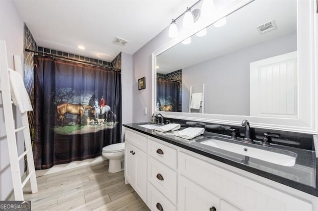 full bath featuring toilet, visible vents, a sink, and wood finished floors