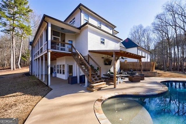 back of property with an outdoor pool, ceiling fan, stairs, fence, and a patio area