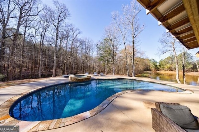 view of swimming pool with a patio area, a water view, and a pool with connected hot tub