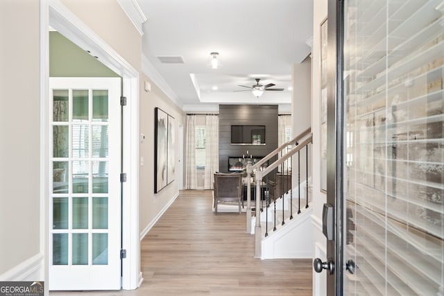 foyer featuring a raised ceiling, crown molding, ceiling fan, and light hardwood / wood-style floors