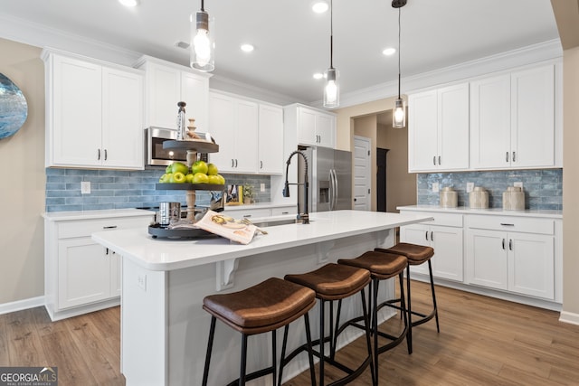 kitchen featuring white cabinetry, decorative light fixtures, and stainless steel appliances