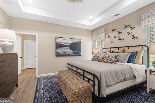 bedroom featuring a tray ceiling and light wood-type flooring