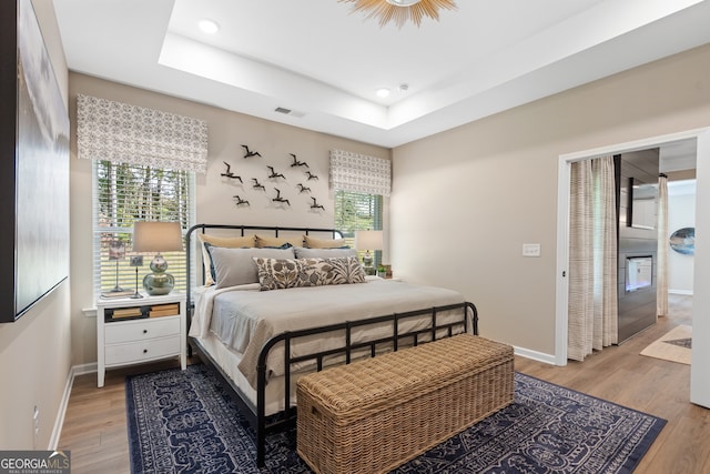 bedroom with a tray ceiling and hardwood / wood-style flooring