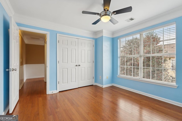 unfurnished bedroom featuring crown molding, ceiling fan, hardwood / wood-style floors, and a closet