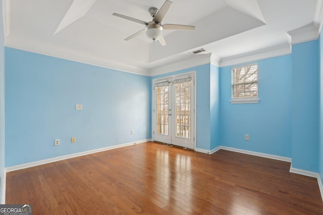 empty room with french doors, ceiling fan, a tray ceiling, and hardwood / wood-style floors