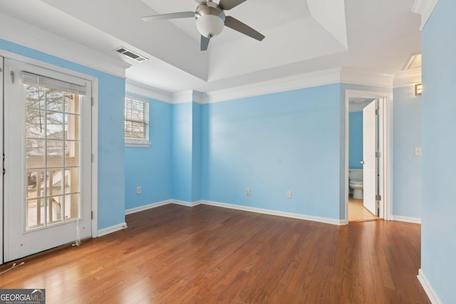 unfurnished room with crown molding, ceiling fan, wood-type flooring, and a tray ceiling