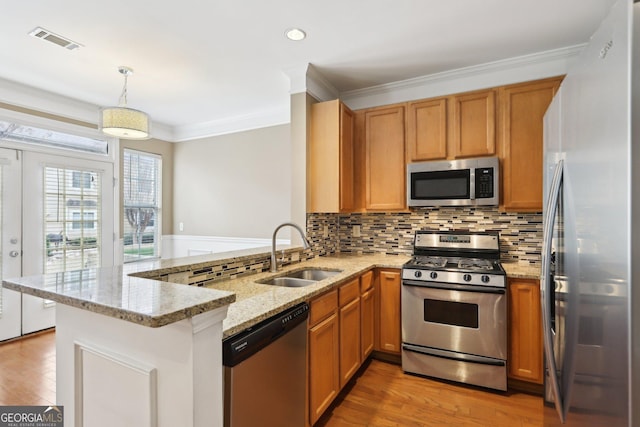 kitchen with appliances with stainless steel finishes, decorative light fixtures, kitchen peninsula, and sink