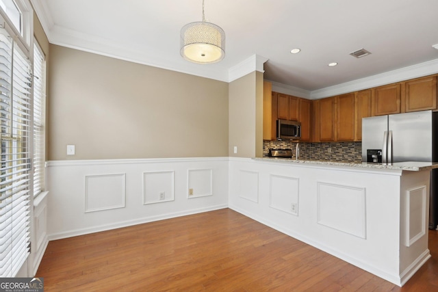 kitchen featuring light stone counters, ornamental molding, decorative light fixtures, and kitchen peninsula