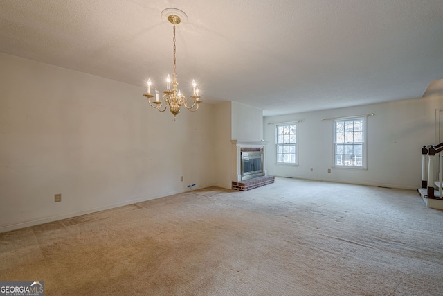 unfurnished living room featuring an inviting chandelier, a brick fireplace, light colored carpet, and a textured ceiling