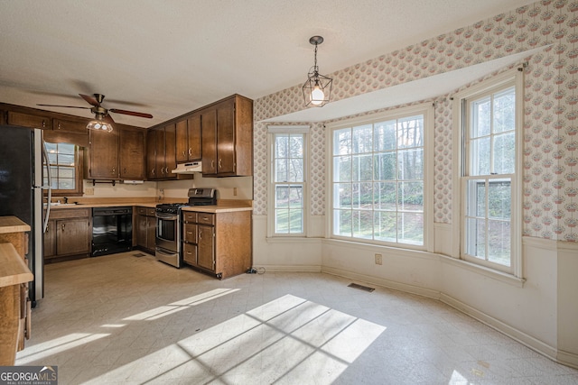 kitchen with sink, hanging light fixtures, ceiling fan, stainless steel appliances, and a textured ceiling