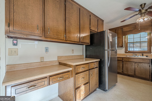 kitchen with sink, a textured ceiling, stainless steel refrigerator, and ceiling fan