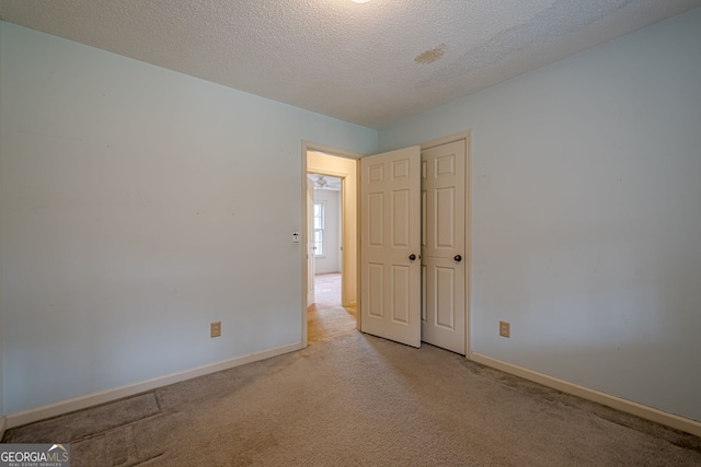 spare room featuring light carpet and a textured ceiling