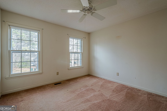 spare room featuring light carpet, ceiling fan, and a textured ceiling