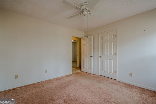 unfurnished bedroom featuring ceiling fan, light carpet, and a textured ceiling