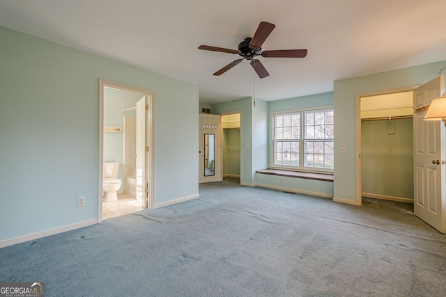 unfurnished bedroom featuring ceiling fan, light colored carpet, and ensuite bath