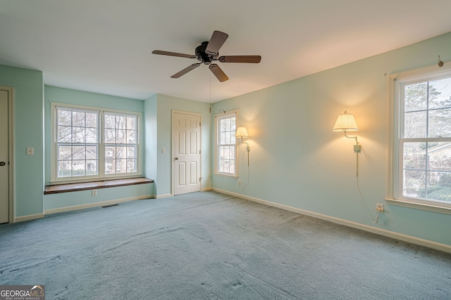 spare room featuring ceiling fan, light carpet, and a wealth of natural light