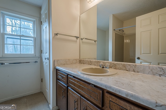 bathroom featuring walk in shower, vanity, and a textured ceiling