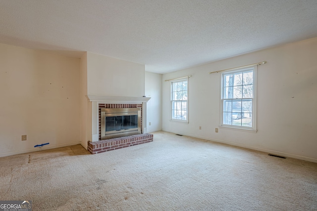 unfurnished living room featuring light carpet, a brick fireplace, and a textured ceiling