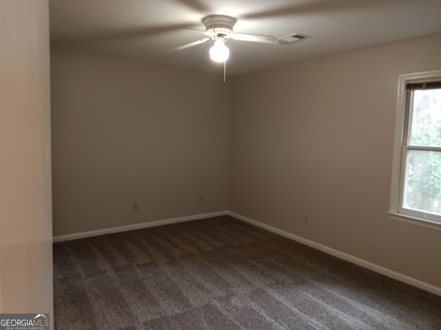 empty room with ceiling fan and dark colored carpet