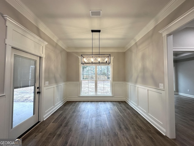 unfurnished dining area with dark wood-type flooring, ornamental molding, and a chandelier