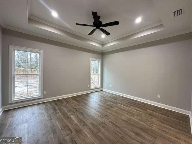 unfurnished room featuring dark wood-type flooring, ornamental molding, and a raised ceiling