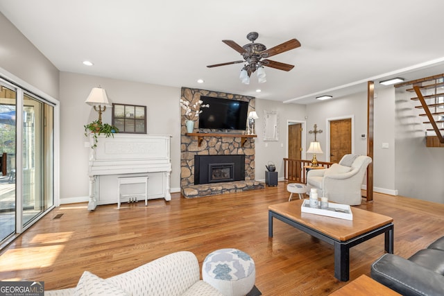 living room featuring ceiling fan, a fireplace, and light wood-type flooring