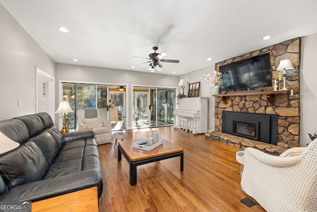 living room featuring hardwood / wood-style flooring, ceiling fan, and a fireplace