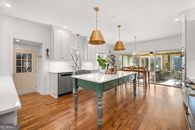 kitchen featuring dishwasher, white cabinetry, light hardwood / wood-style floors, a kitchen island, and decorative light fixtures