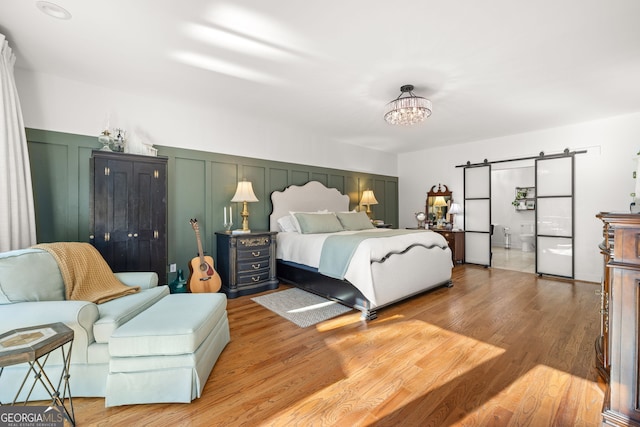 bedroom featuring an inviting chandelier, a barn door, and hardwood / wood-style floors