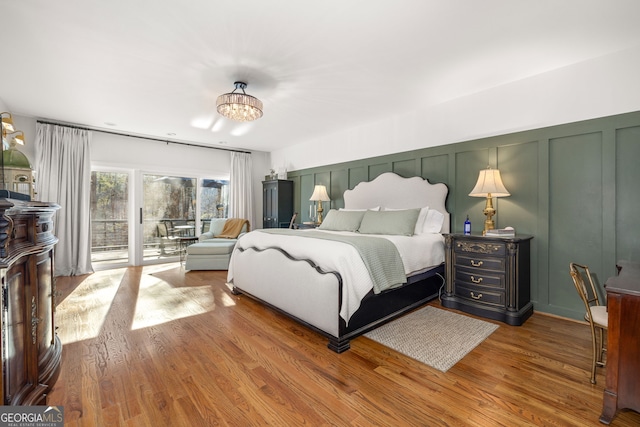 bedroom with access to exterior, a notable chandelier, and wood-type flooring