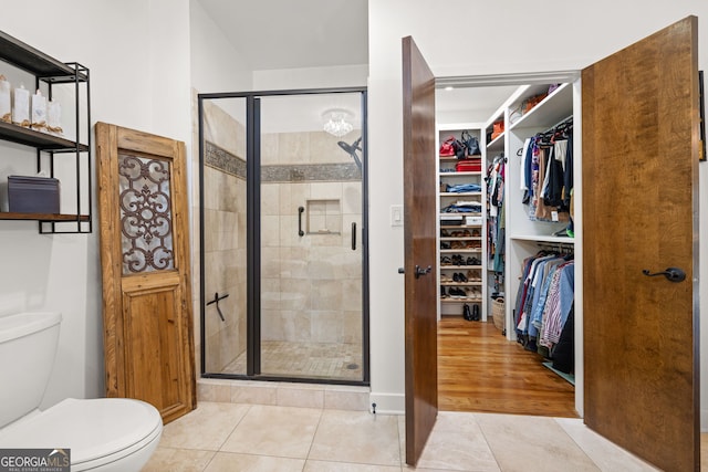 bathroom with tile patterned flooring, a shower with shower door, and toilet