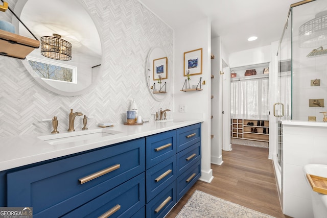 bathroom featuring hardwood / wood-style flooring, vanity, tasteful backsplash, and walk in shower