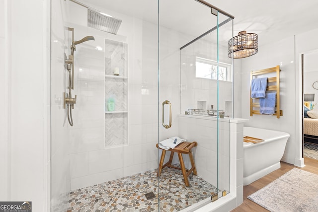 bathroom featuring plus walk in shower and hardwood / wood-style floors