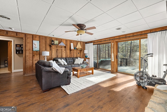 living room featuring ceiling fan, wooden walls, and dark hardwood / wood-style flooring