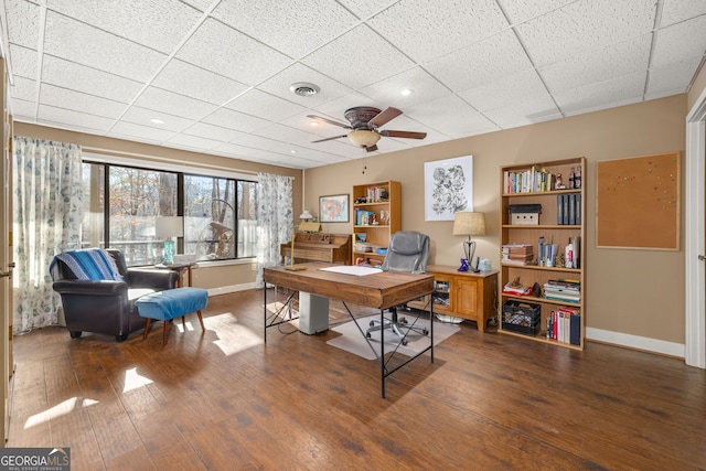 office space with dark wood-type flooring, a drop ceiling, and ceiling fan