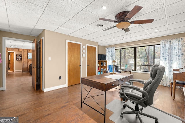 office space with ceiling fan, dark hardwood / wood-style flooring, and a drop ceiling