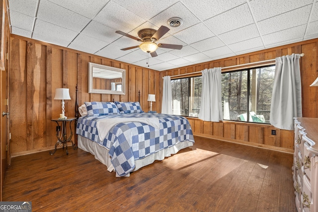 bedroom with ceiling fan, hardwood / wood-style floors, and wood walls