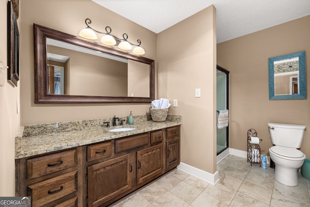 bathroom with vanity, toilet, a shower with door, and a textured ceiling