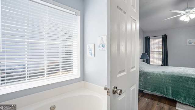 bathroom with hardwood / wood-style flooring, ceiling fan, and a tub to relax in