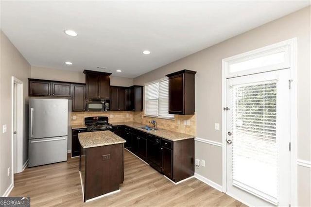 kitchen with a center island, backsplash, dark brown cabinetry, and black appliances