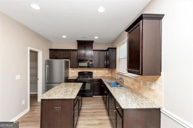 kitchen featuring light hardwood / wood-style flooring, sink, a kitchen island, and black appliances