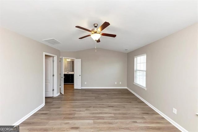 empty room with ceiling fan, vaulted ceiling, and light wood-type flooring