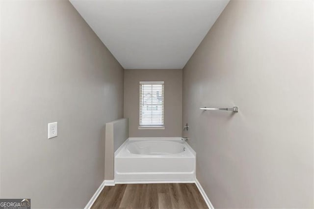 bathroom with a bath and hardwood / wood-style floors