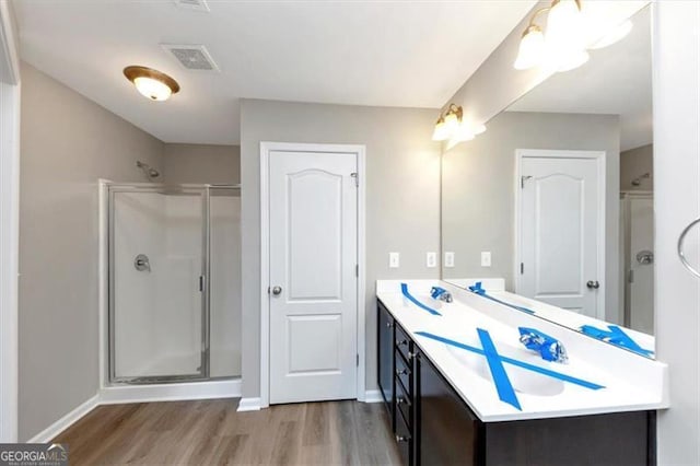 bathroom featuring vanity, wood-type flooring, and a shower with shower door