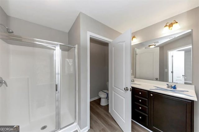 bathroom with walk in shower, wood-type flooring, toilet, and vanity