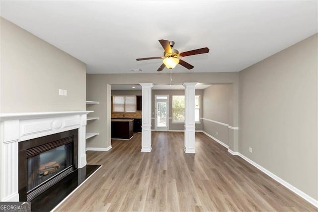 unfurnished living room featuring ceiling fan, light hardwood / wood-style floors, and decorative columns