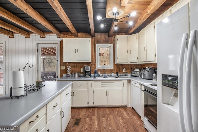 kitchen featuring sink, white cabinetry, light wood-type flooring, white appliances, and beam ceiling