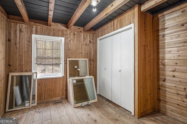 miscellaneous room featuring wooden walls, wooden ceiling, beam ceiling, and light hardwood / wood-style flooring