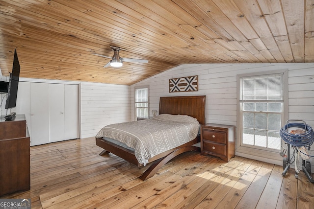 bedroom with vaulted ceiling, wood walls, wood ceiling, and light hardwood / wood-style flooring